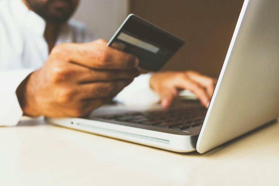 Payment card held at a laptop for an online purchase